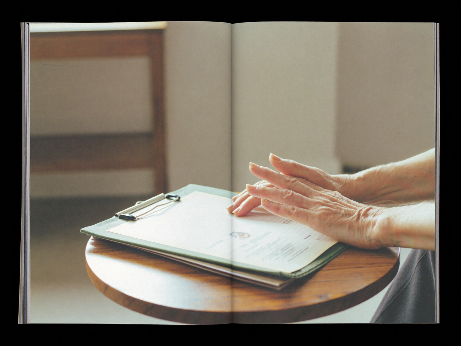 Practitioner’s hands holding an unmarked folder on a wooden studio side table